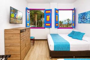 a bedroom with a bed and a dresser and two windows at La Posada de la Plaza in Salento
