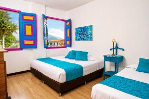 two beds in a room with two windows at La Posada de la Plaza in Salento