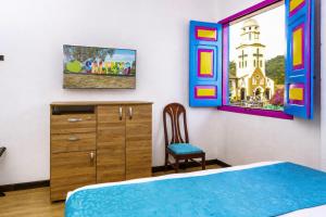 a bedroom with a bed and a dresser and a chair at La Posada de la Plaza in Salento