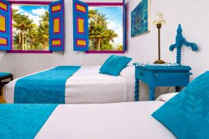 a bedroom with two beds and a table with a lamp at La Posada de la Plaza in Salento