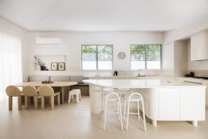a white kitchen with a table and stools at Coastal Haven on Witta in Noosa Heads