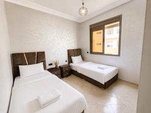 a bedroom with two beds and a window at Modern and Cozy in Agadir
