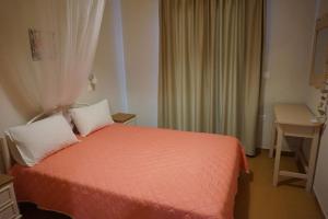 a bedroom with a orange bed with white pillows at Kapitan in Arillas