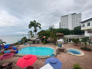 a swimming pool with umbrellas and the ocean at Hotel Barbasquillo in Manta