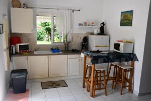 a kitchen with white cabinets and a table with stools at VILLA CREOLE in Gourbeyre