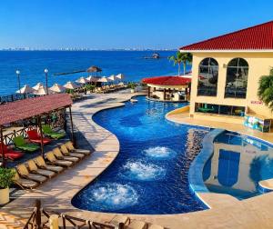 a resort pool with chairs and the ocean in the background at Caribbean apartment in Cancún