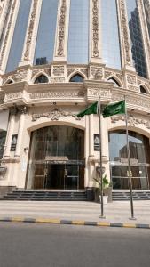 a building with two green flags in front of it at فندق الأرضُ المتميزه - Land Prime -1 in Mecca