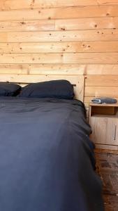 a bed in a room with a wooden wall at Карпатські Мандри in Verkhovyna