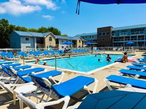a pool with blue and white chairs and people in it at Put-in-Bay Poolview Condo #2 in Put-in-Bay