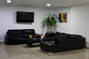 a living room with black leather furniture and a flat screen tv at Hotel Roosevelt Plaza in Cali +36 photos