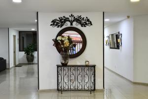 a hallway with a mirror and a vase with flowers at Hotel Roosevelt Plaza in Cali