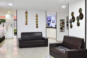 a lobby with two black leather couches and plates on the wall at Hotel Roosevelt Plaza in Cali