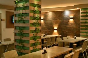 a restaurant with tables and chairs and a wall with plants at Hotel Roosevelt Plaza in Cali