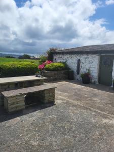 a picnic bench in front of a building with flowers at Rose Meadow Cottage in Liscannor