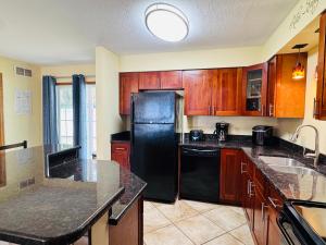a kitchen with a black refrigerator and wooden cabinets at Put-in-Bay Poolview Condo #4 in Put-in-Bay +32 photos