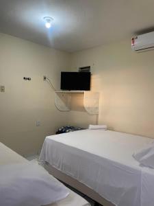 a room with two beds and a tv on the wall at Pousada BR 423 in Garanhuns
