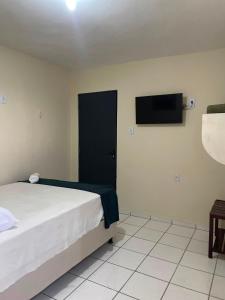 a bedroom with a bed and a tv on the wall at Pousada BR 423 in Garanhuns