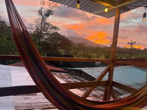 a hammock on a deck with a sunset in the background at Blackout Party Hostel and Experiences in Fortuna