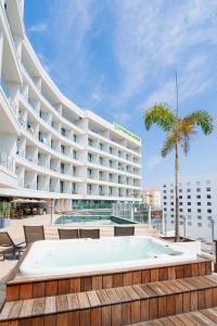 a large hotel with a pool and a palm tree at Wyndham Garden Mazatlan Marina in Mazatlán