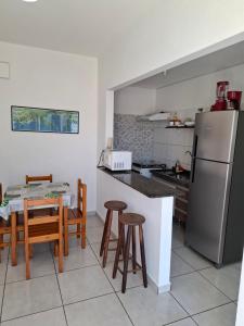 a kitchen with a refrigerator and a table and chairs at Apartamentos Gratitude in Ubatuba
