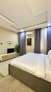 a bedroom with a large bed and a tv at Leria Living luxury 2 bedroom wuye, Abuja in Ankuru