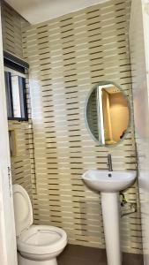a bathroom with a toilet and a sink and a mirror at Leria Living luxury 2 bedroom wuye, Abuja in Ankuru +11 photos