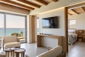 a bedroom with a bed and a tv and a couch at Pefkian Ethos Hotel & Suites in Pefki