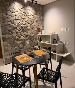 a dining room with a table and chairs and a stone wall at Espaço Sonhos da Serra in Bananeiras