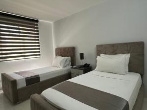 a hotel room with two beds and a window at Hotel Roosevelt Plaza in Cali