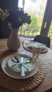 a table with a plate and a vase with flowers at Wald Living in Baiersbronn