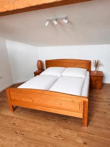 a bedroom with a wooden bed with white sheets at Apartment am Starnberger See in Tutzing