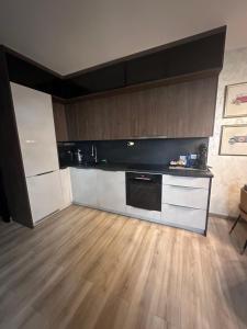 a kitchen with white cabinets and a wooden floor at Apartmán Maťko in Levice