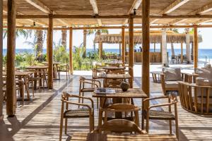 an empty restaurant with tables and chairs and the ocean at Pefkian Ethos Hotel & Suites in Pefki