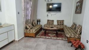 a living room with couches and a table and a tv at Location salamandre in Mostaganem