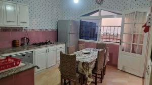 a kitchen with a table with chairs and a refrigerator at Location salamandre in Mostaganem
