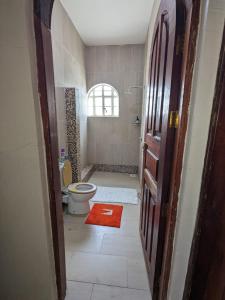 a bathroom with a toilet and a red rug at White Hill Penthouse in Kisumu