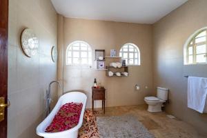 a bathroom with a tub and a toilet and windows at White Hill Penthouse in Kisumu