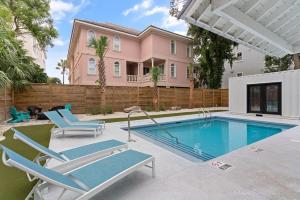 a swimming pool with two chairs and a house at Coastal Escape for 2 - Pool, Fire Pit & Beach Access in Saint Simons Island
