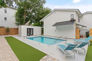 a swimming pool with two chairs and a house at Coastal Escape for 2 - Pool, Fire Pit & Beach Access in Saint Simons Island +21 photos