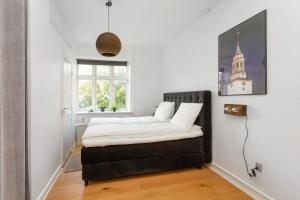 a bedroom with a bed with white sheets and a window at Central Jylland Suite in Aalborg