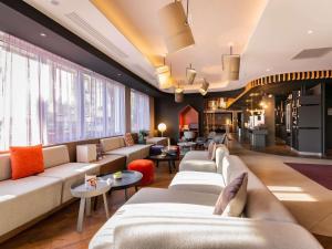 a living room with couches and tables and windows at Novotel Suites Colmar Centre in Colmar