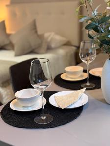 a table with two wine glasses and plates on it at Nova Studio Dpto nuevo a pasos de Av Alemania in Temuco