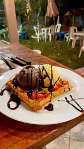 a white plate with ice cream and chocolate sauce at Pousada Horizontes de Bonito in Bonito