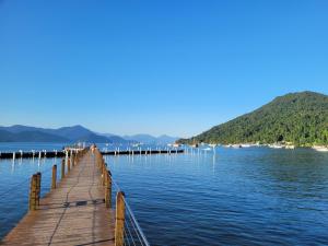 a wooden dock in the water with a mountain at Apartamentos Gratitude in Ubatuba