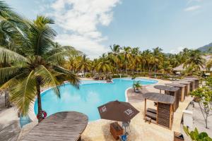 ein Bild von einem Resort-Pool mit Tischen und Palmen in der Unterkunft Tay Beach Hotel Tayrona in Buritaca