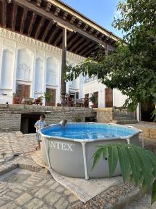 a boy sitting in a boat in front of a house at Merik Boutique in Bukhara +24 photos