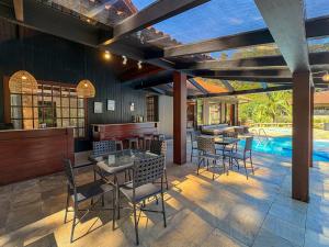 an outdoor patio with tables and chairs and a swimming pool at Casa 02 Vale Boa Vista - Casa em Condomínio Exclusivo com Vista para as Montanhas e Área de Lazer Completa in Teresópolis