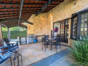 a patio with a table and chairs and a kitchen at Casa 02 Vale Boa Vista - Casa em Condomínio Exclusivo com Vista para as Montanhas e Área de Lazer Completa in Teresópolis