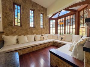a living room with a large white couch in a stone wall at Casa 02 Vale Boa Vista - Casa em Condomínio Exclusivo com Vista para as Montanhas e Área de Lazer Completa in Teresópolis