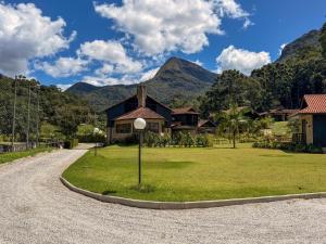 a house in a field with mountains in the background at Casa 02 Vale Boa Vista - Casa em Condomínio Exclusivo com Vista para as Montanhas e Área de Lazer Completa in Teresópolis